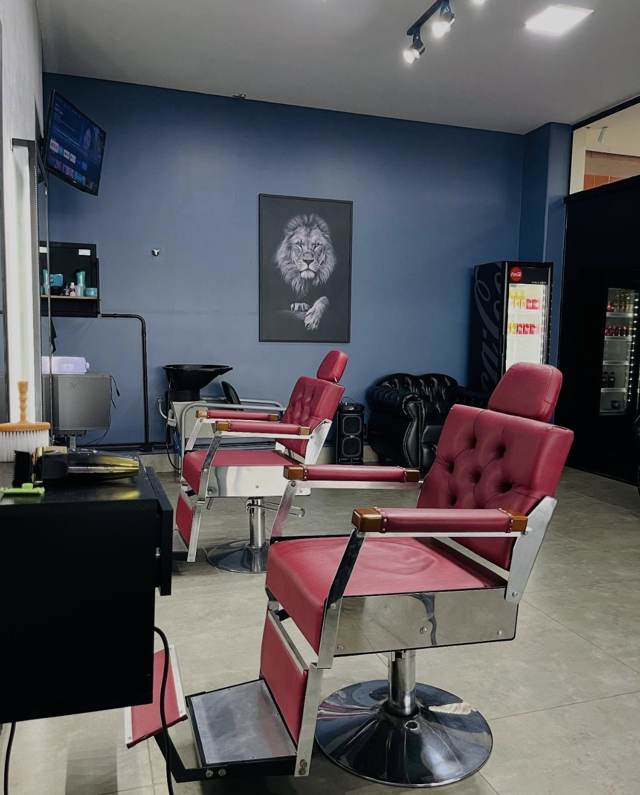 Interior da barbearia com poltronas vinho e quadro de leão